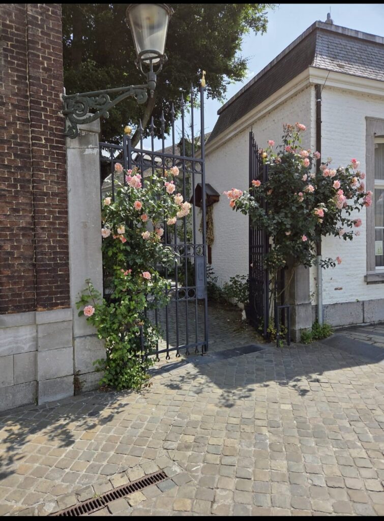 De toegangspoort aan het Keizer Karelplein, met rozen langs de muur. Achter de poort ligt de ingang van het café.